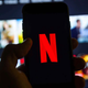 A person holds a smartphone featuring the Netflix "N" logo.